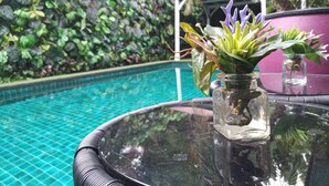Una mesa con cubierta de vidrio, una planta en maceta y un florero de vidrio.