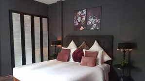Un dormitorio moderno con una cama grande, paredes oscuras y dos lámparas de pared.