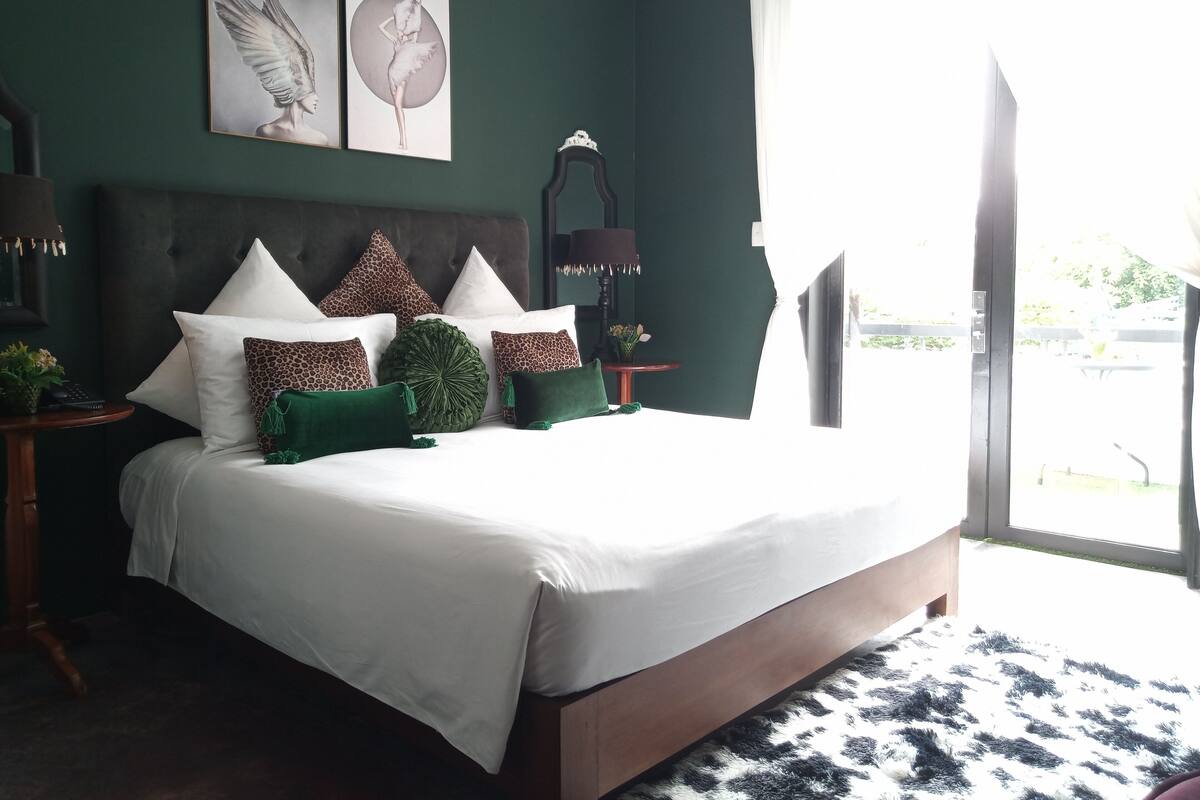 Une chambre à coucher avec un grand lit, une tête de lit et une table de chevet avec une lampe.