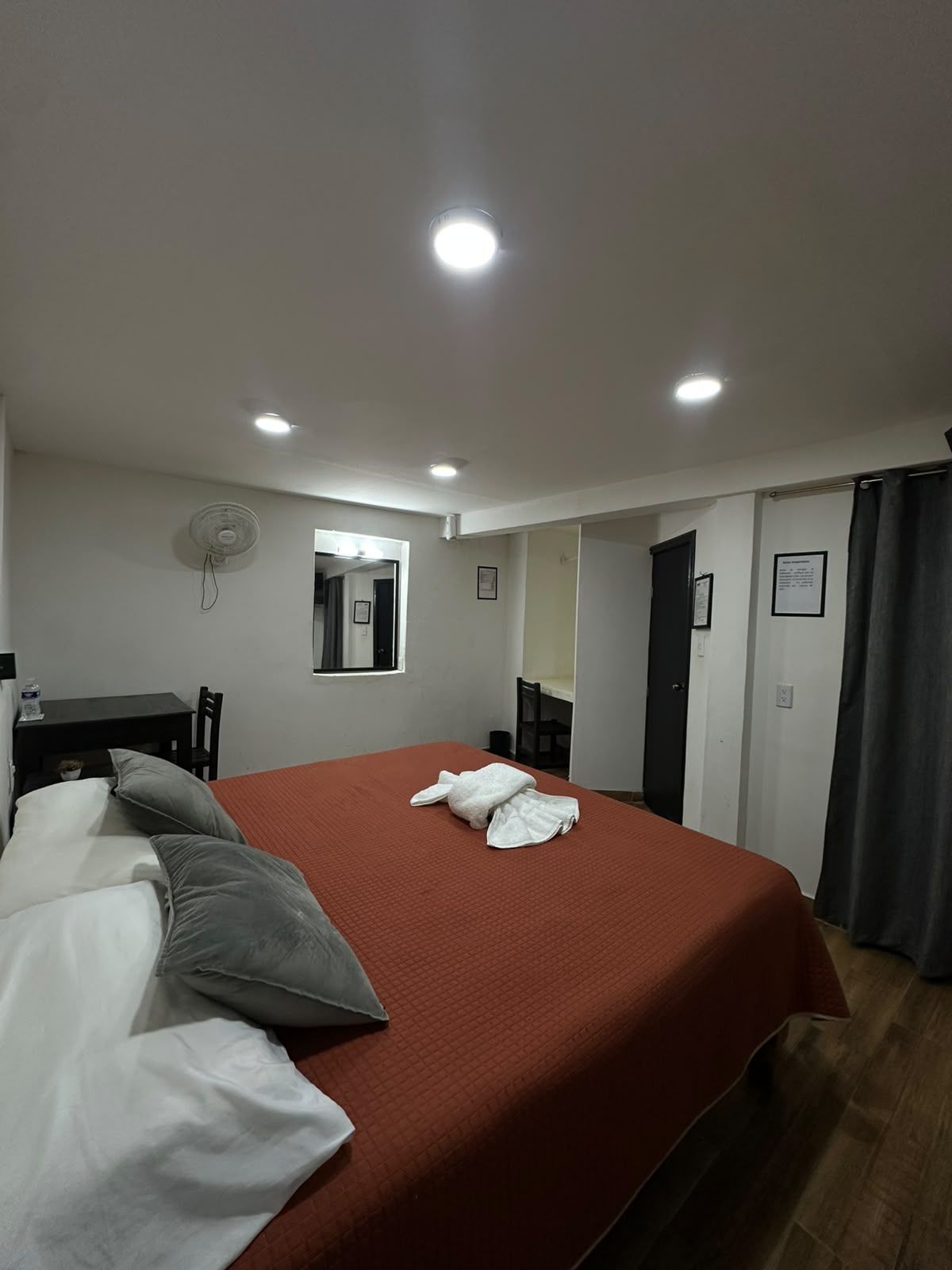 Een hotelkamer met een bed, een bureau, een stoel, een spiegel en een deur.