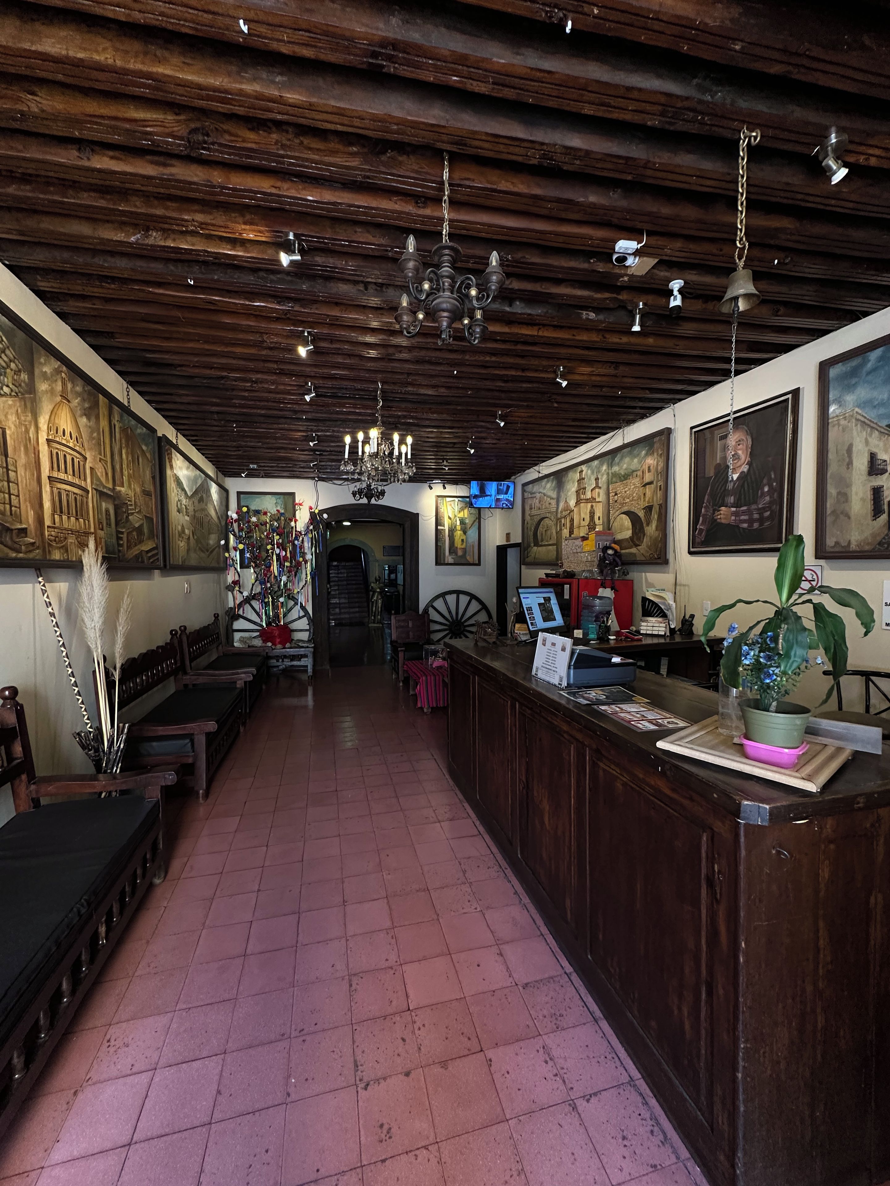 Interior de un restaurante con vigas de madera en el techo, una barra larga y obras de arte en las paredes.
