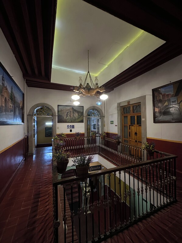 A spacious lobby with a high ceiling, a chandelier, and a central seating area with a railing.