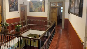 Un hall d’entrée spacieux avec un espace central ouvert, des portes en bois et un lustre.