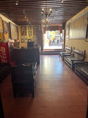 Un vestíbulo espacioso con techo alto, vigas de madera y una araña. Hay áreas de descanso con bancos y un refrigerador de Coca-Cola.
