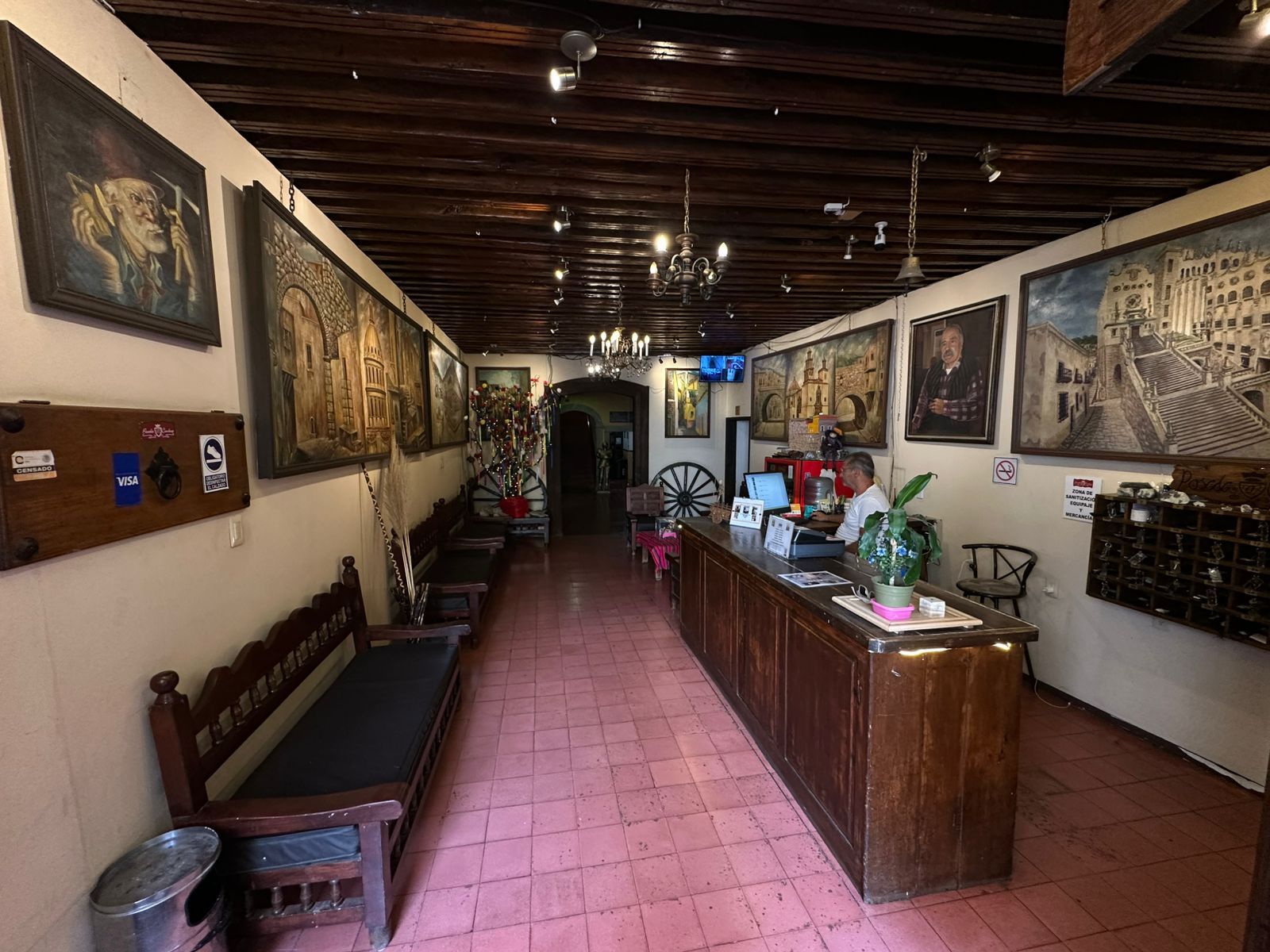 Un vestíbulo de hotel con mostrador de recepción, zona de estar y obras de arte en las paredes.