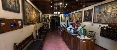 Un vestíbulo de hotel con mostrador de recepción, zona de estar y obras de arte en las paredes.