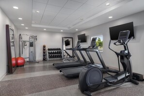 Ein Fitnessstudio mit Laufbändern, Kraftgeräten und Gymbällen.
