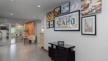 A hotel lobby with a reception desk, framed artwork on the wall, and a glimpse of the dining area in the background.
