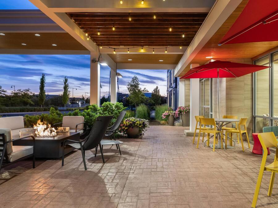 An outdoor patio with a fire feature, seating, and a view of the cityscape.