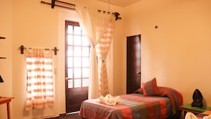 A hotel room with a bed, a nightstand, a window with curtains, and a door. - Posada Don Mario (Oaxaca)