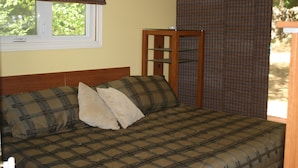 A bed with a plaid bedspread, a wooden headboard, and a window with blinds. - Honey Harbour Cottage (Georgian Bay)