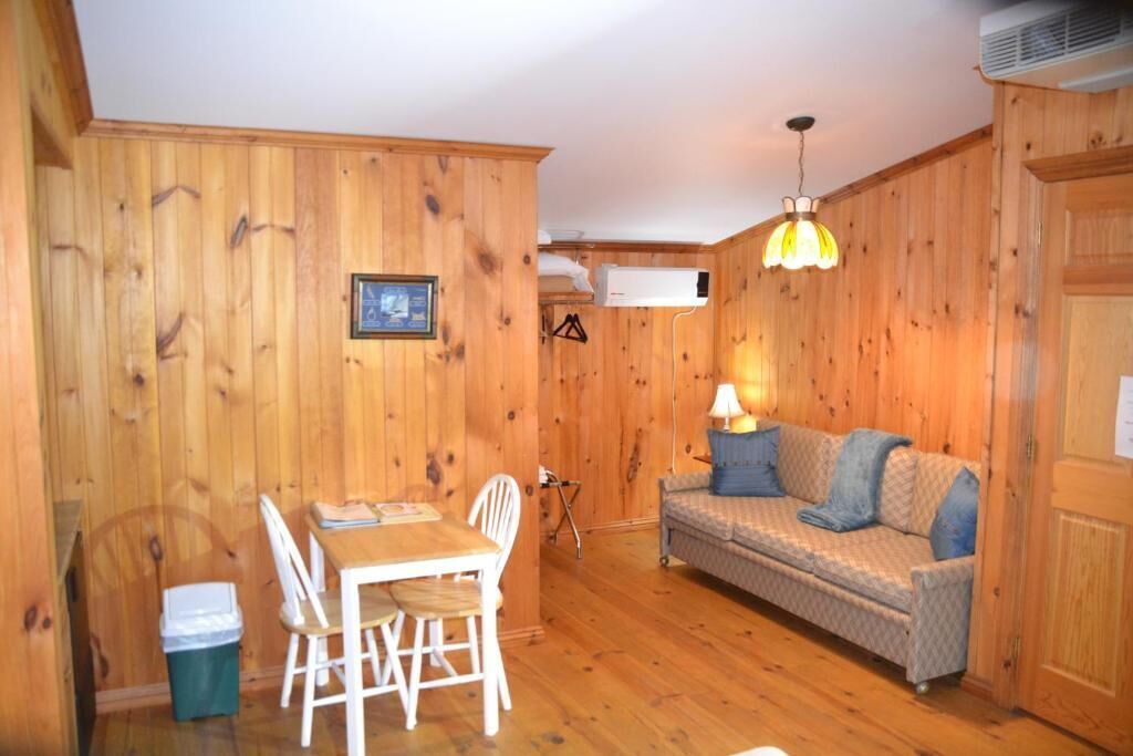 Un interior de madera con una mesa de comedor, sillas, un sofá y una lámpara colgante.