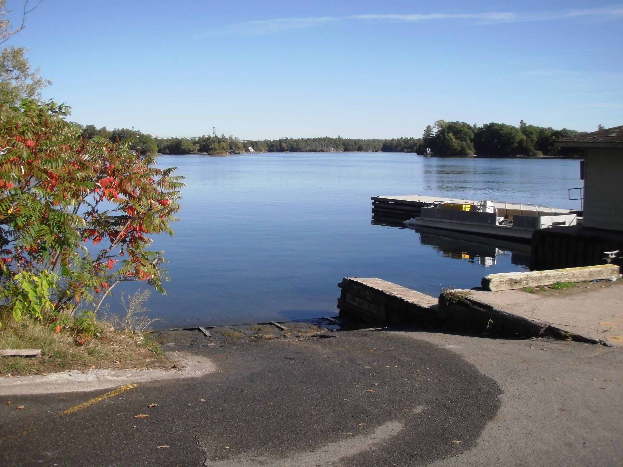 Um lago calmo com um píer e uma área de estacionamento ao primeiro plano.