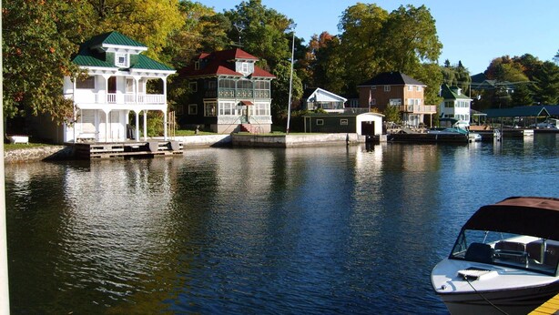 A waterfront property with a dock, a boat, and multiple buildings with distinct architectural styles.