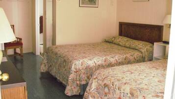 A hotel room with two beds, a chair, a lamp, and a painting on the wall.