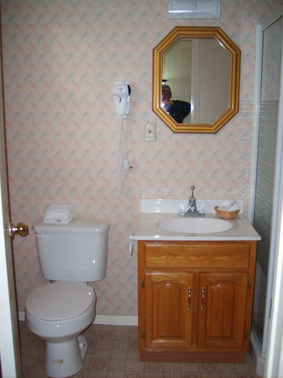Un baño con inodoro, lavamanos, mueble de madera y espejo.