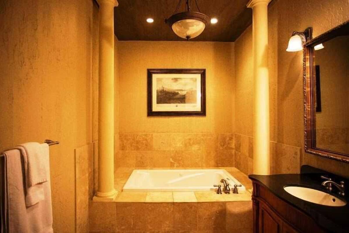A bathroom with a large bathtub, a sink, and a framed picture on the wall.