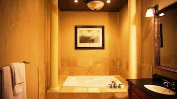 A bathroom with a large bathtub, a sink, and a framed picture on the wall.