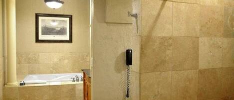 Un bagno con una vasca, una doccia e un telefono a muro.