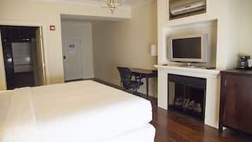 A hotel room with a bed, a television, a fireplace, and a desk with a chair.