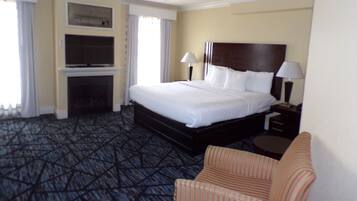 A hotel room with a large bed, two bedside lamps, a TV, and a chair.