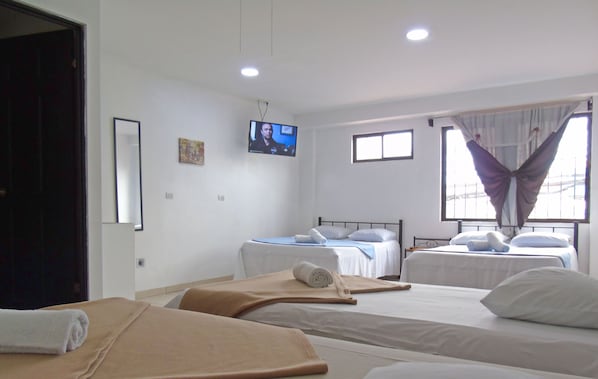 A hotel room with two beds, a TV on the wall, and a window with curtains. - Hotel Quinta Avenida (San José)