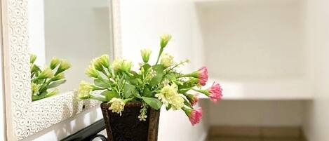 Une table noire sur laquelle se trouve un vase rectangulaire contenant des fleurs et une télécommande.