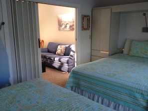 Un dormitorio con dos camas, un sofá y una puerta que da a otra habitación.