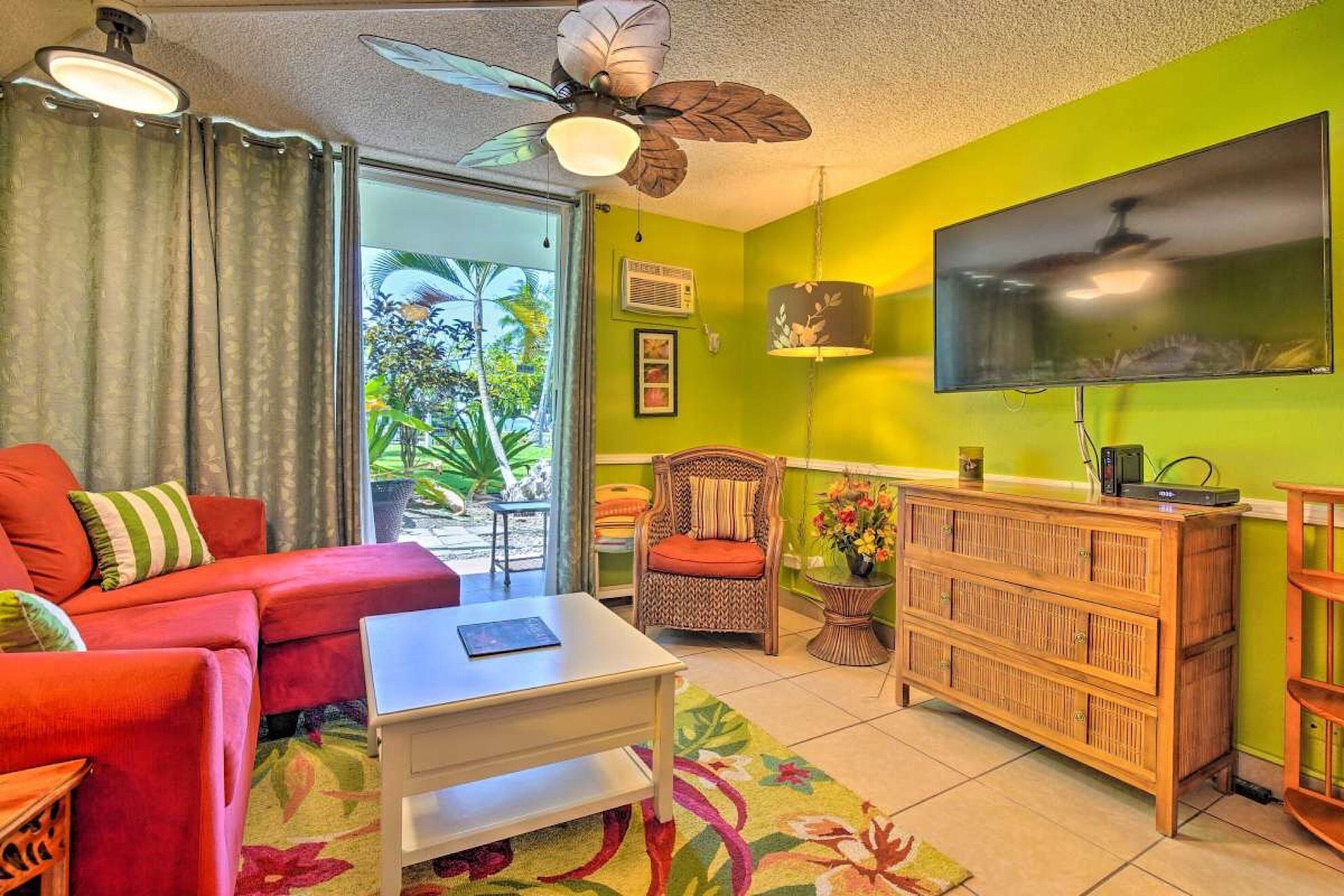A living room with a red sofa, a white coffee table, a wooden cabinet, and a ceiling fan.
