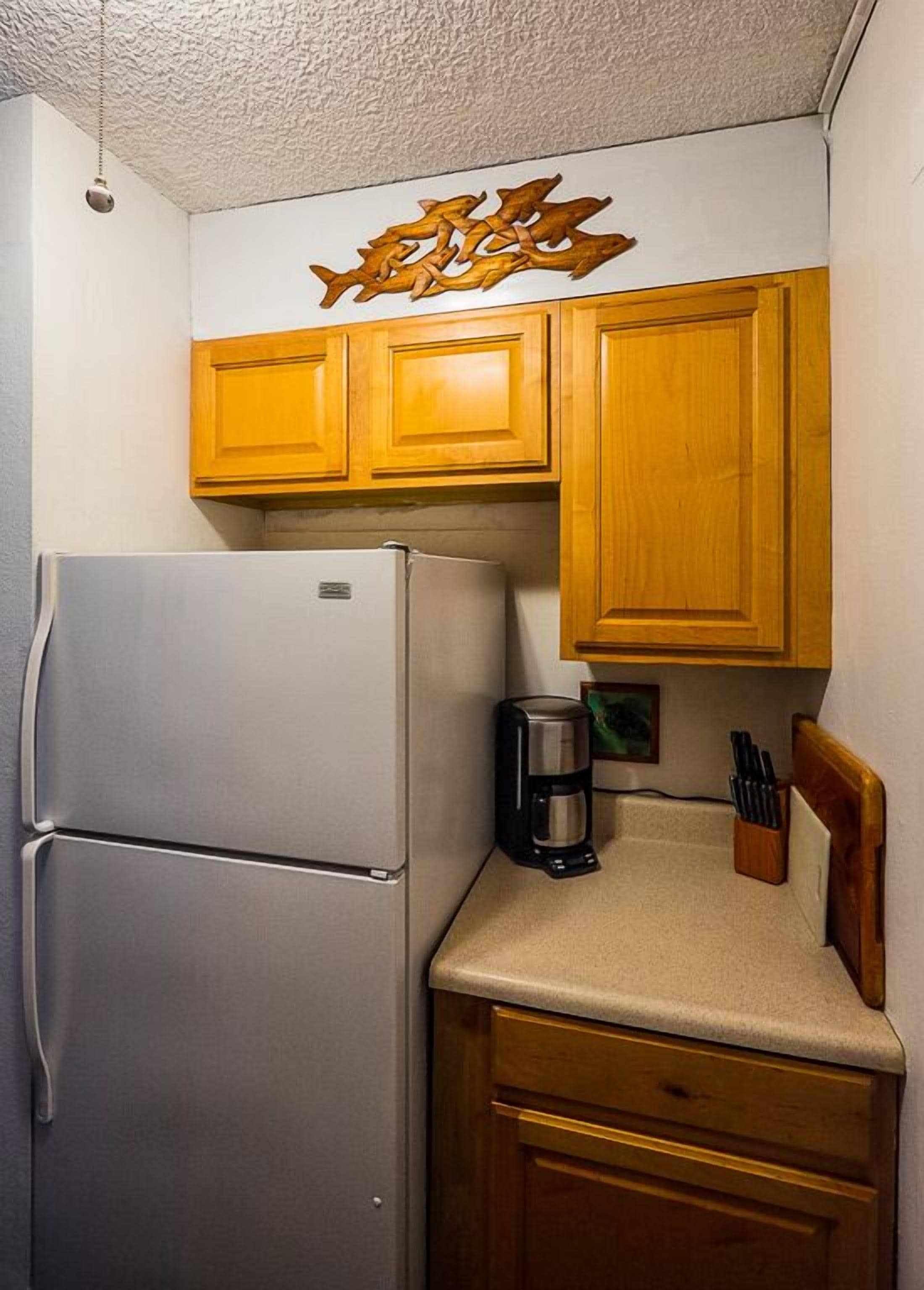 A kitchen with wooden cabinets, a white refrigerator, and a coffee maker on the counter.
