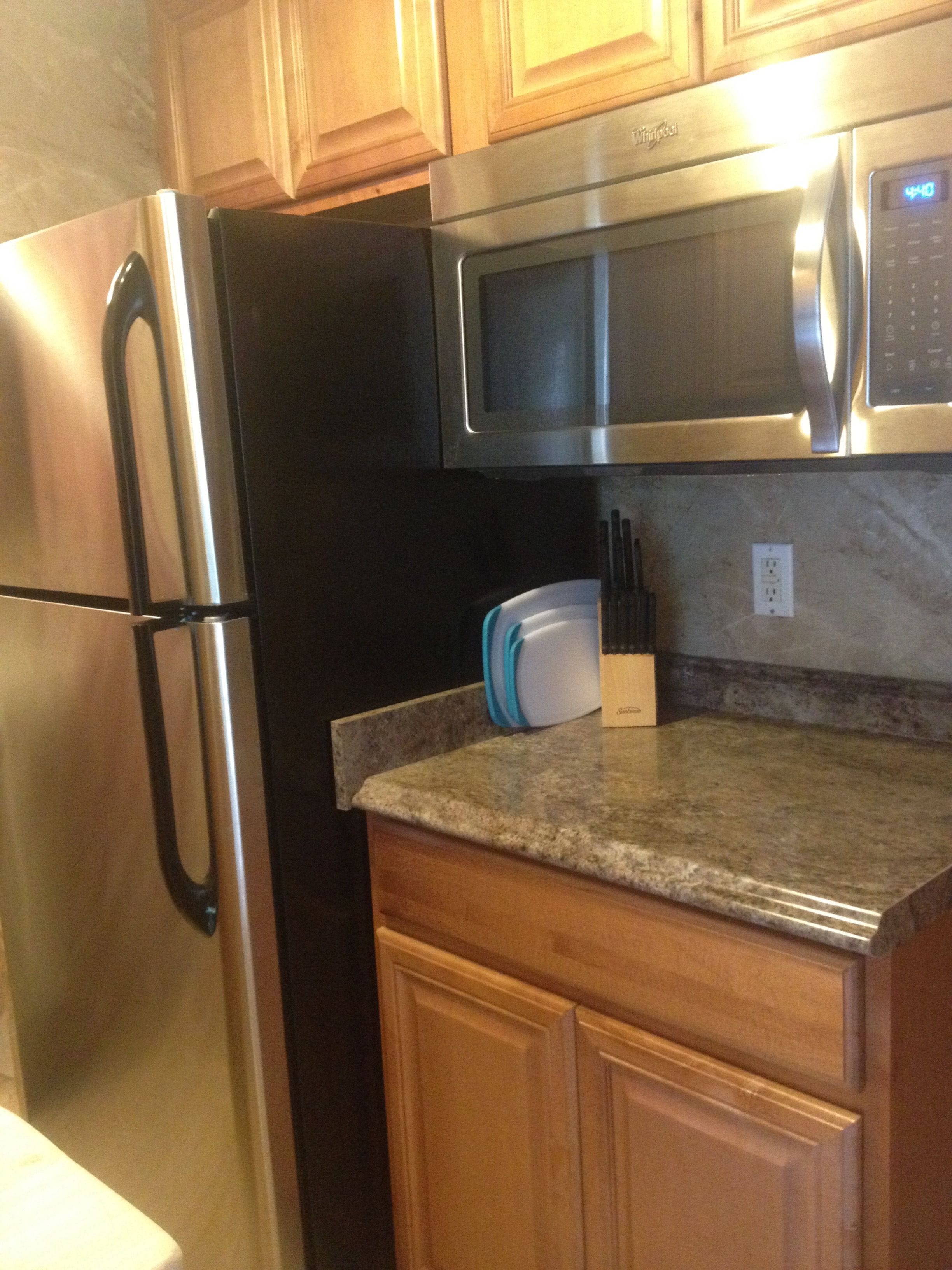 A kitchen with stainless steel appliances, wooden cabinets, and a granite countertop.