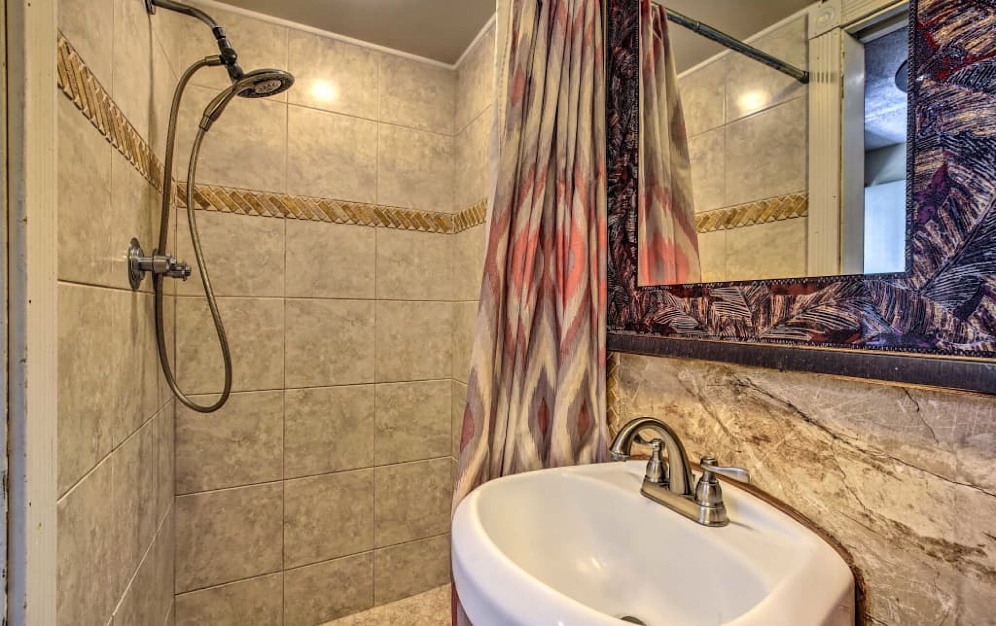A bathroom with a shower, a sink, and a mirror.