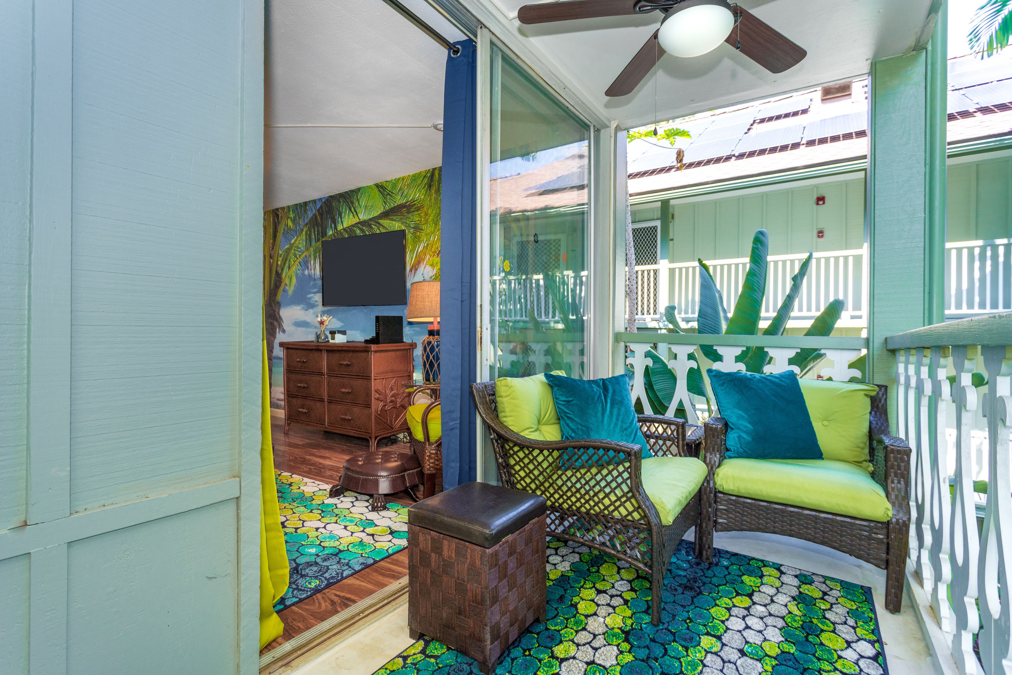 A room with a ceiling fan, wicker furniture, a patterned rug, and a view of the outside.