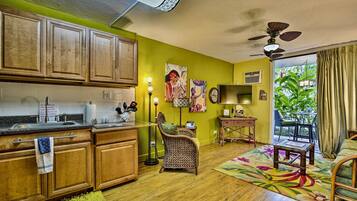 A kitchen with wooden cabinets, a dining area with a chair, a table, and a colorful rug.