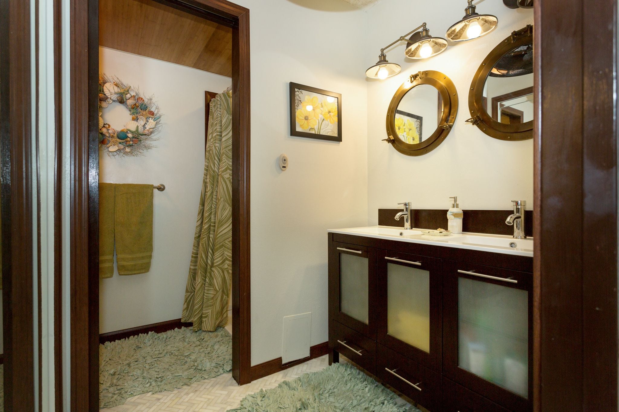 A bathroom with a wooden vanity, two sinks, a mirror, and a shower curtain.