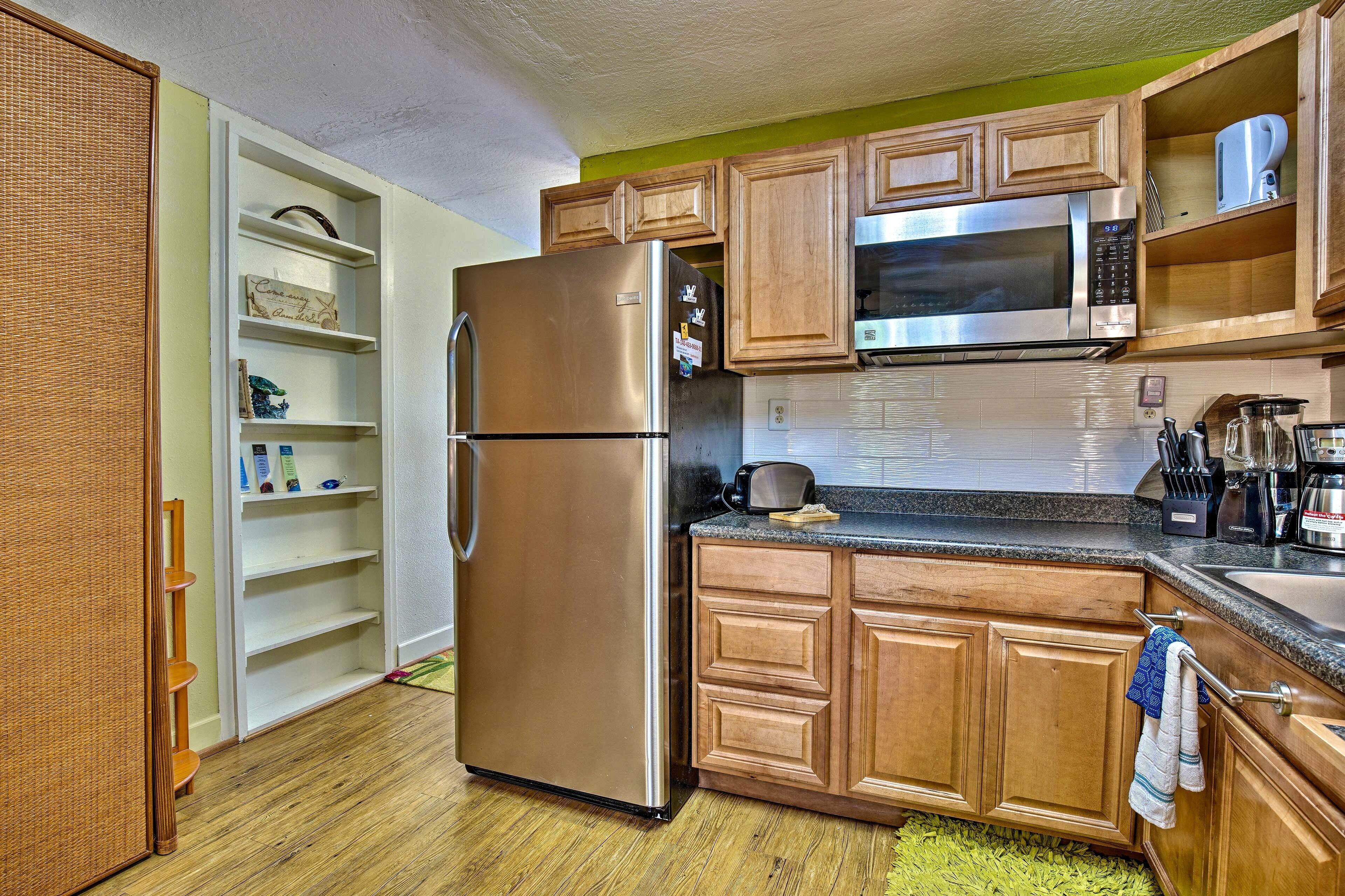A kitchen with wooden cabinets, a stainless steel refrigerator, a microwave, and a sink.