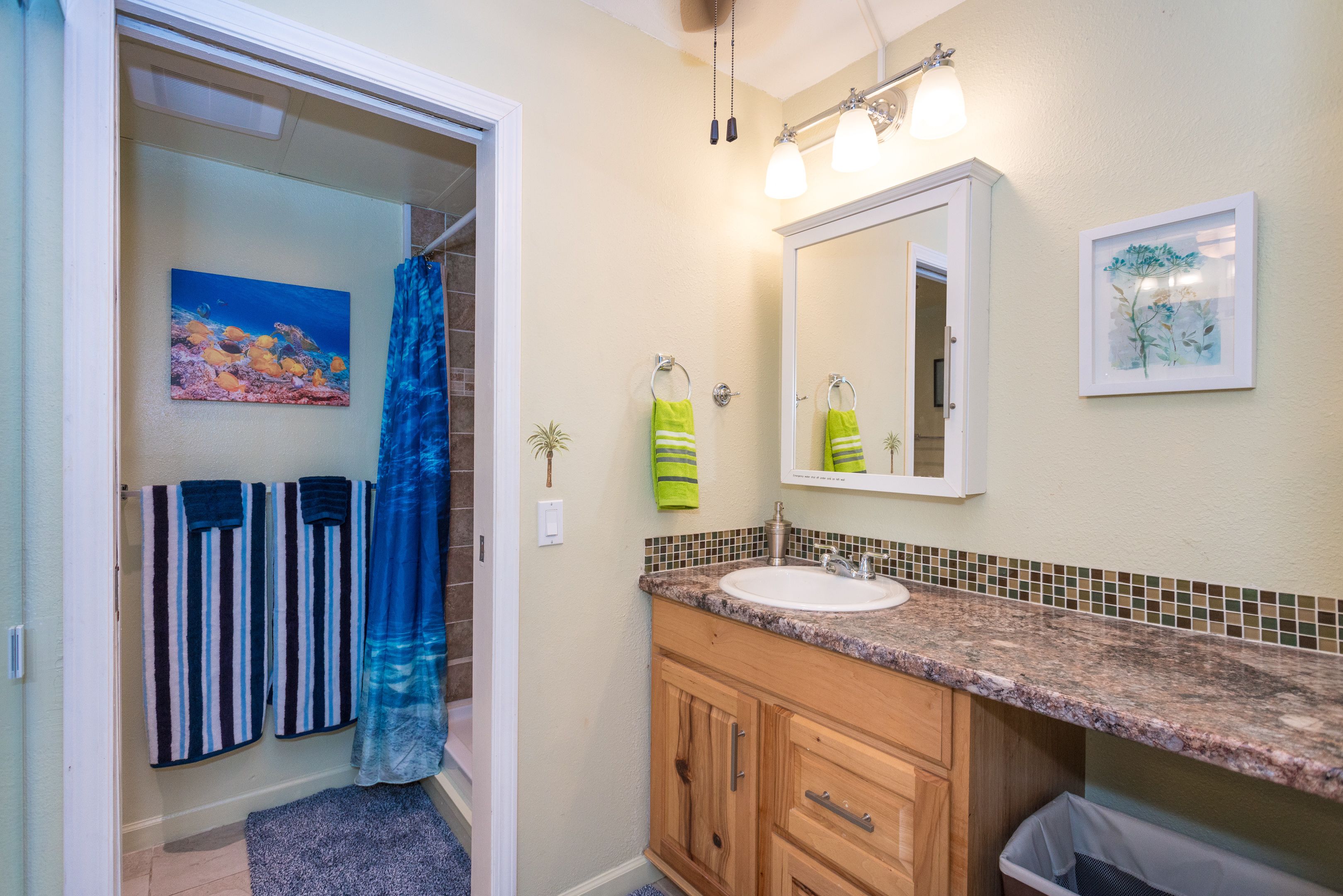 A bathroom with a shower, a sink, a mirror, and a towel rack.