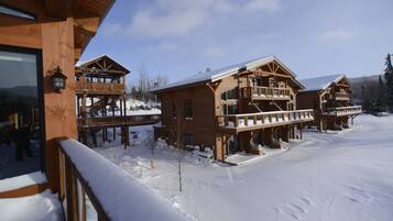 A wooden lodge with multiple balconies and a snowy landscape.