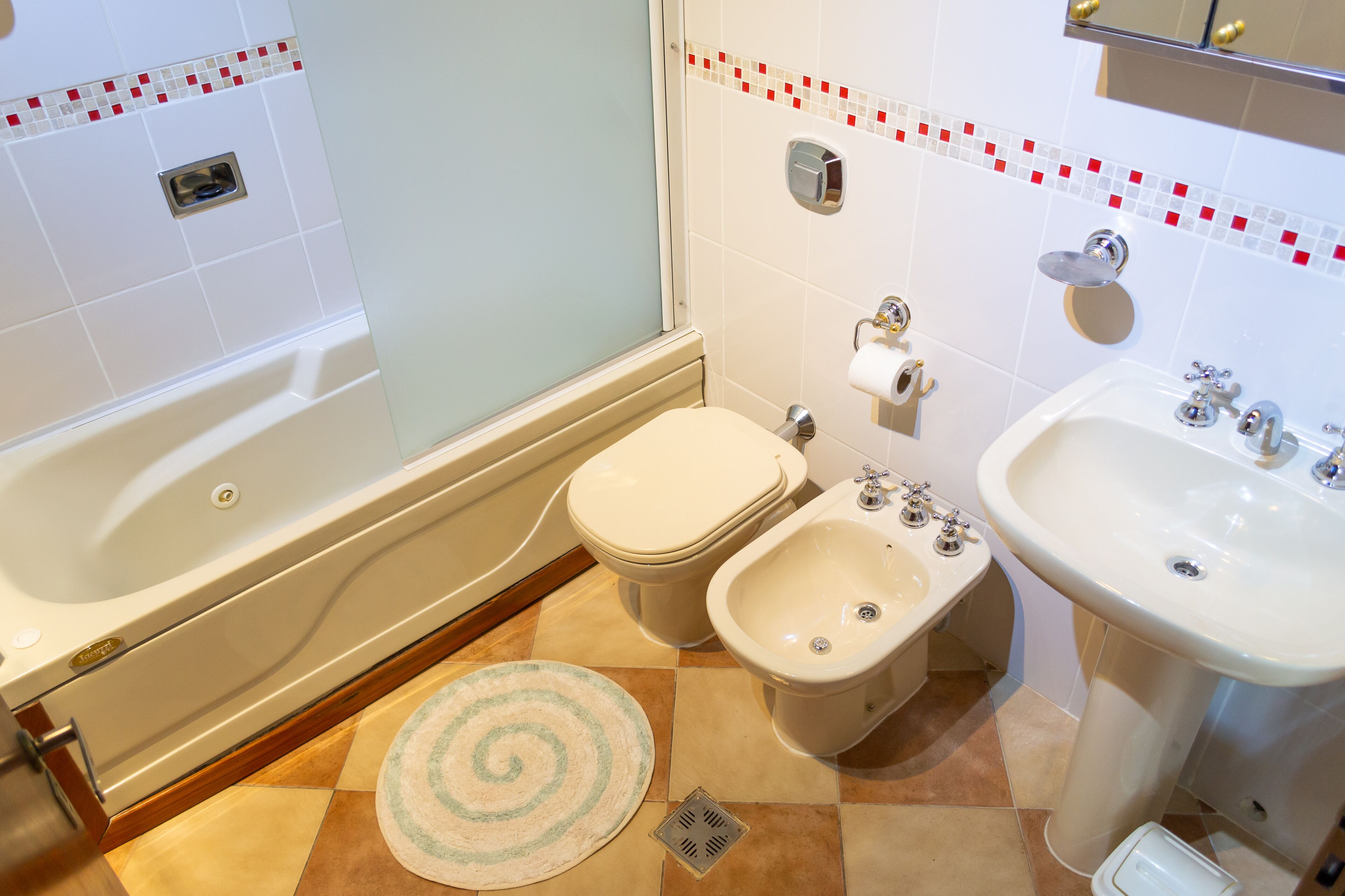 Een badkamer met een bad, toilet, bidet, wastafel en douchegordijn.