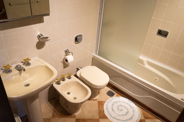 A bathroom with a sink, bidet, toilet, and bathtub.