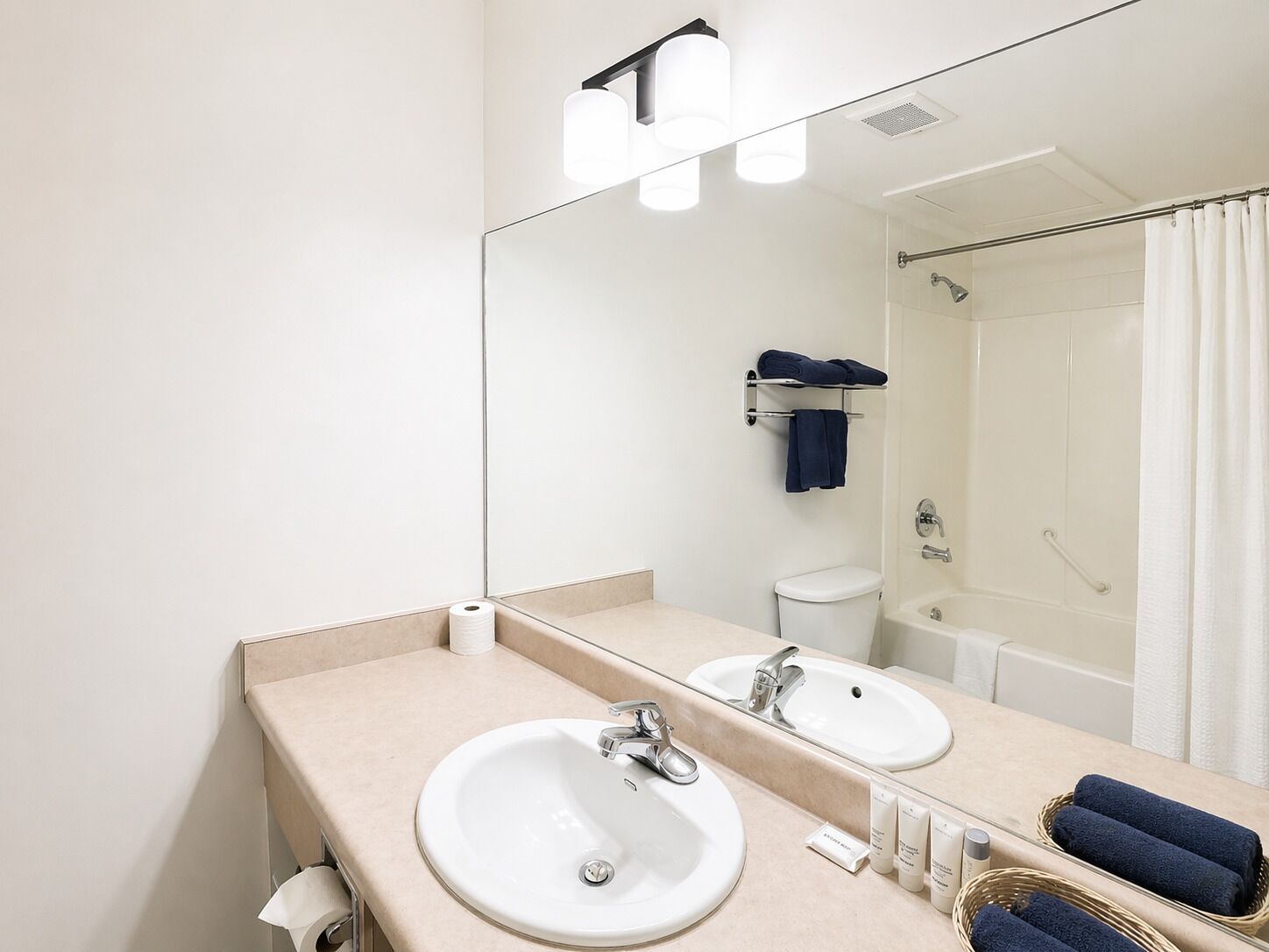 Une salle de bain avec deux lavabos, un miroir, des toilettes et une douche.