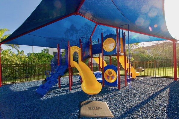 A playground with a climbing structure, slides, and a covered area.