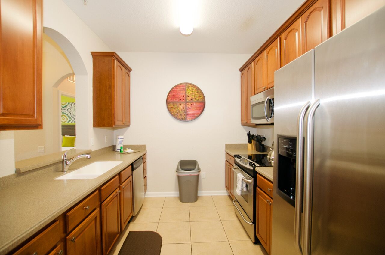 A kitchen with wooden cabinets, stainless steel appliances, a microwave, and a trash can.