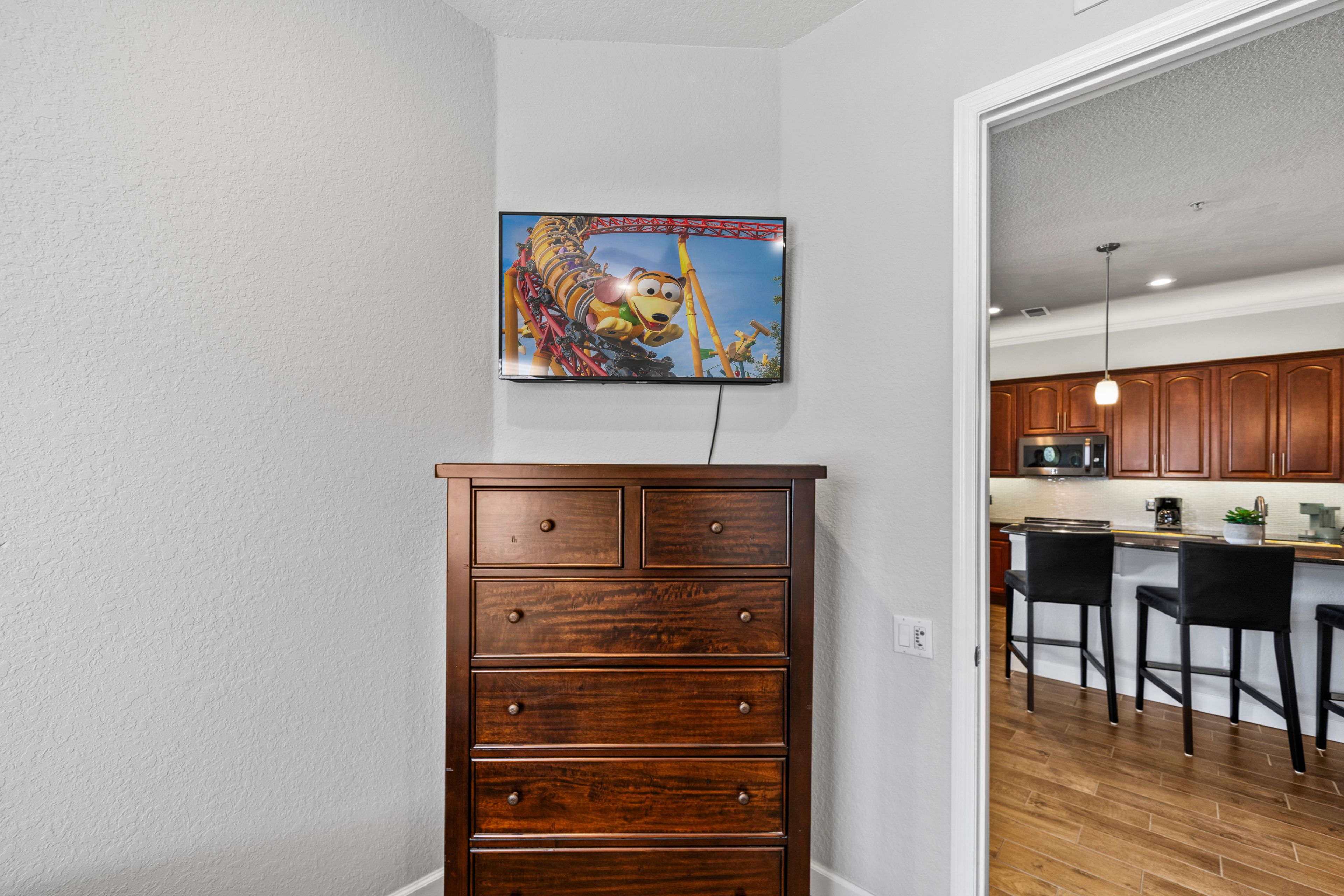 Een moderne keuken met houten kastjes, een magnetron en een bar met barkrukken.