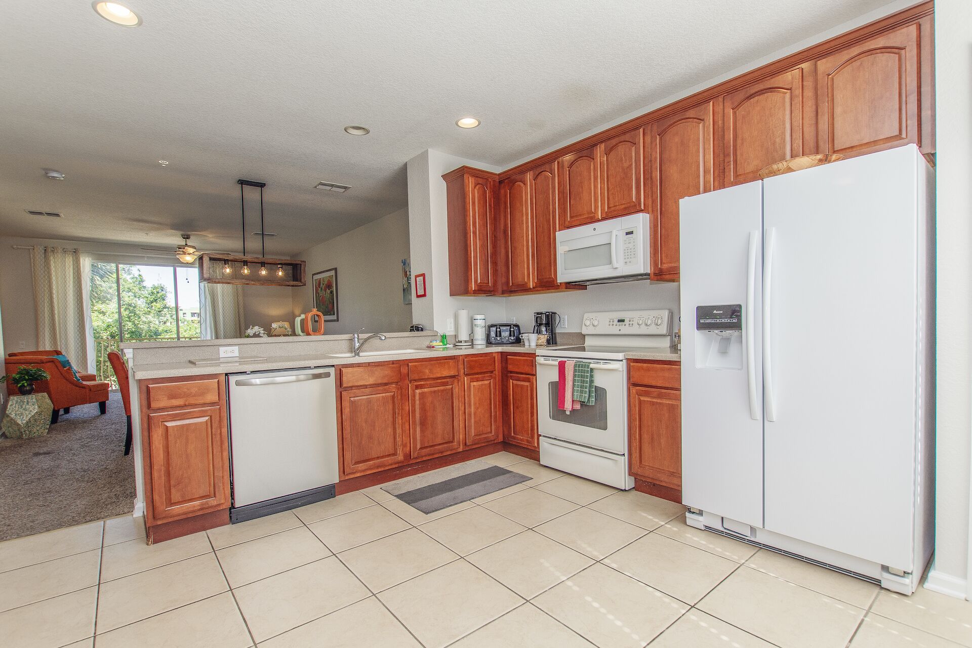 A modern kitchen with wooden cabinets, a white refrigerator, a microwave, and a dishwasher.