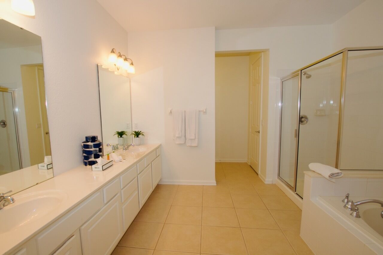 A modern bathroom with a large mirror, a glass shower enclosure, and a white sink.