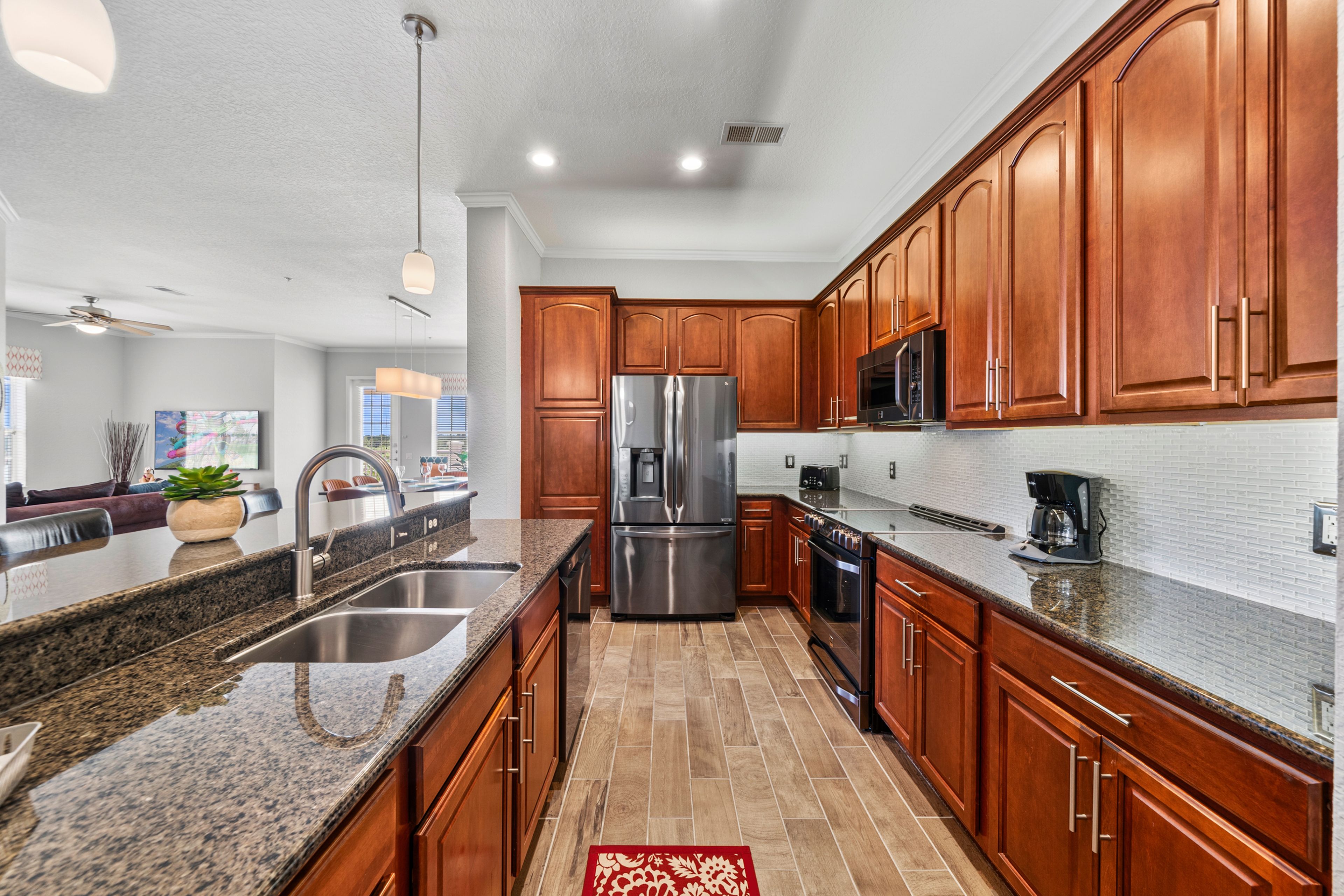 A modern kitchen with granite countertops, stainless steel appliances, and wooden cabinetry.