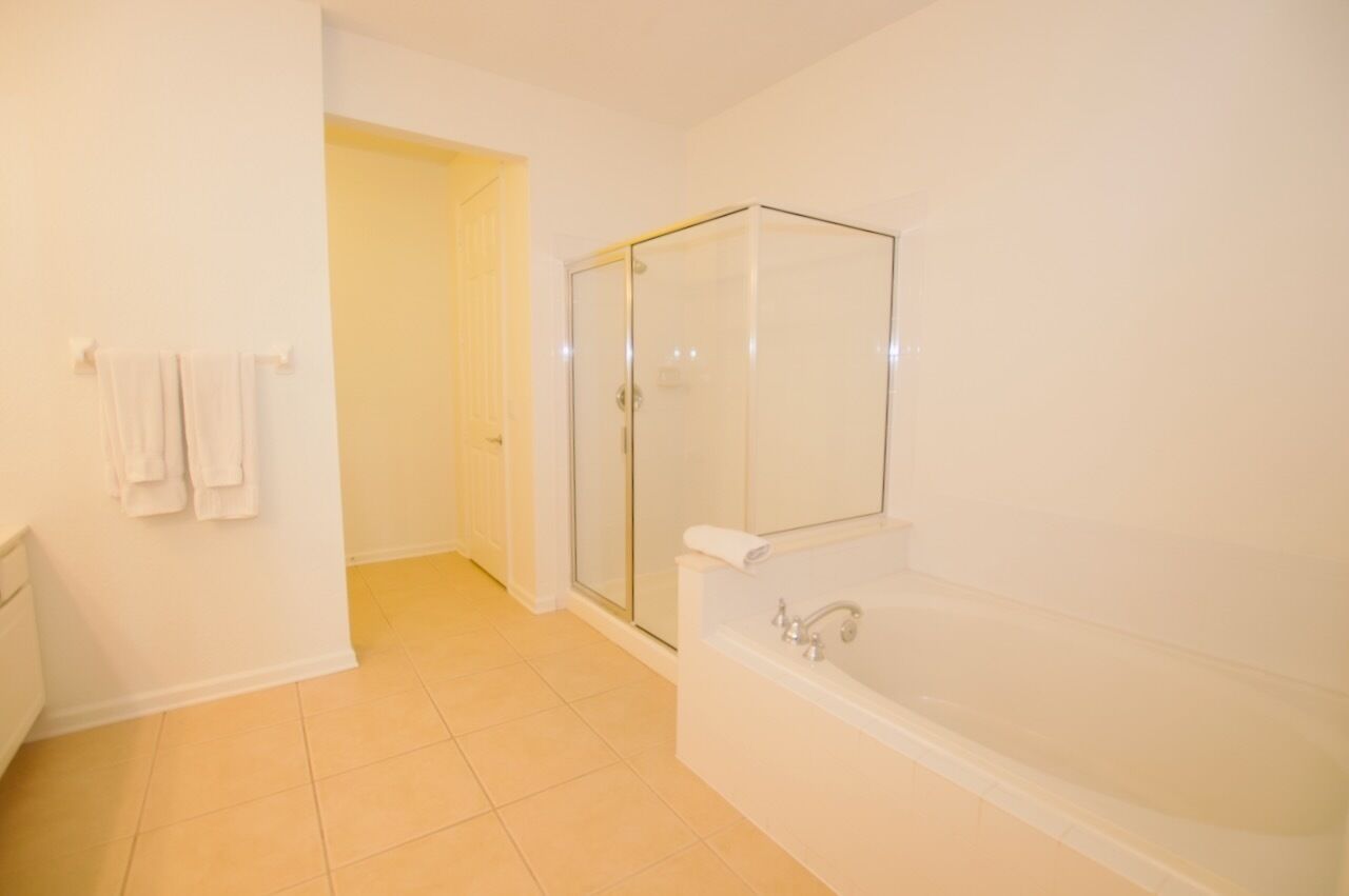 A bathroom with a glass-enclosed shower, a white bathtub, and a towel rack with towels.