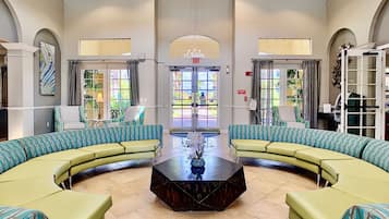 A spacious lobby with a central coffee table, seating area with sofas, and large windows providing natural light.