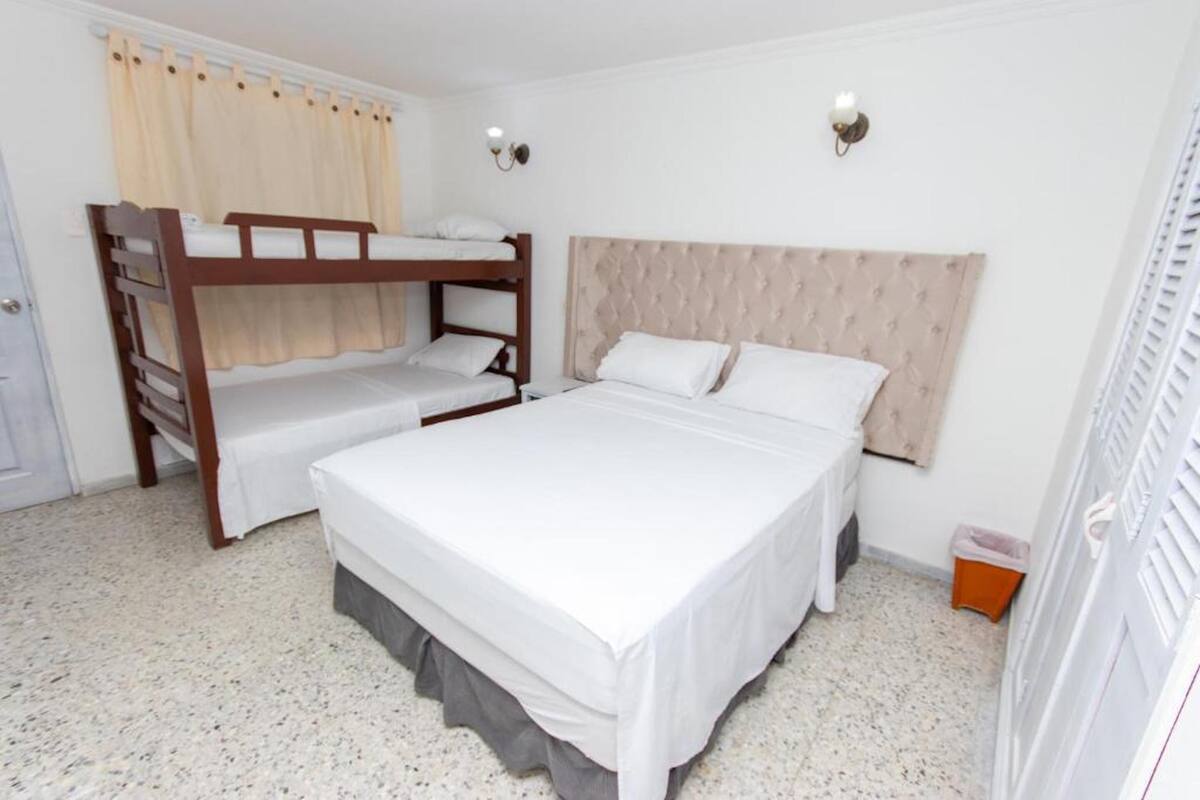 A bedroom with bunk beds, a large bed, and a headboard.